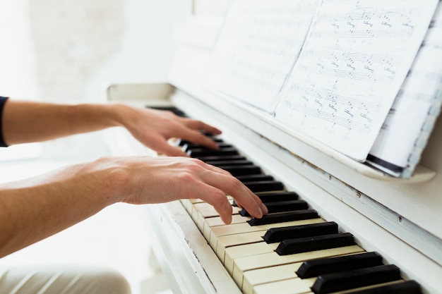 Foto la mano del hombre tocando el piano con notas musicales.