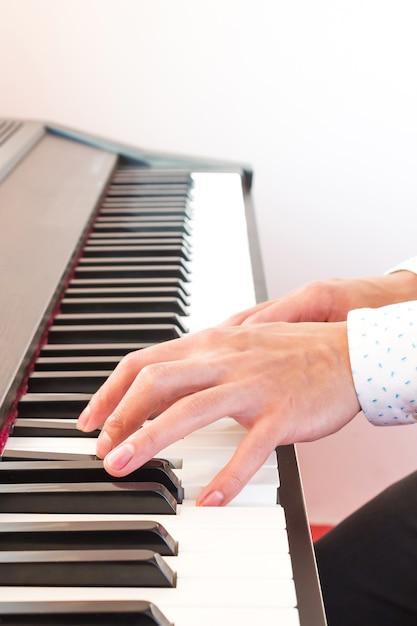 La mano del hombre tocando el piano.