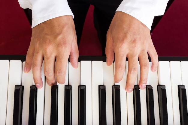 La mano del hombre tocando el piano.
