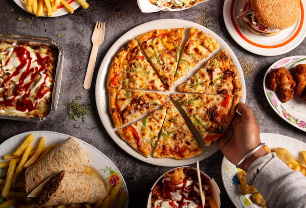 La mano de un hombre toma una rebanada de pizza en la mesa del restaurante de comida rápida