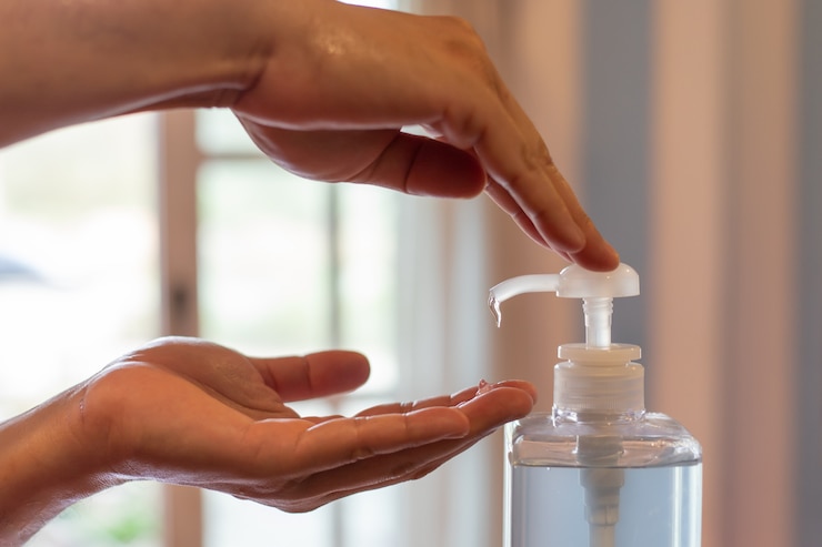 mano de hombre usando dispensador de gel desinfectante para lavado de manos, contra coronavirus novedoso o enfermedad de virus corona (Covid-19) en público interior