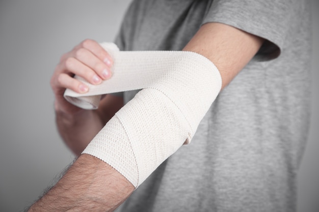 Foto mano de hombre con vendaje elástico en el codo.