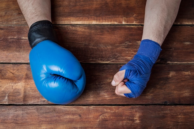 La mano del hombre en vendajes de boxeo y un guante de boxeo sobre un fondo de madera. concepto de entrenamiento para entrenamiento de boxeo o lucha.