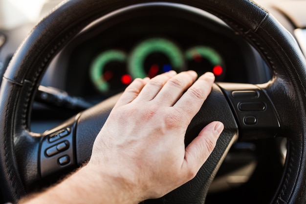 La mano del hombre en el volante del coche.