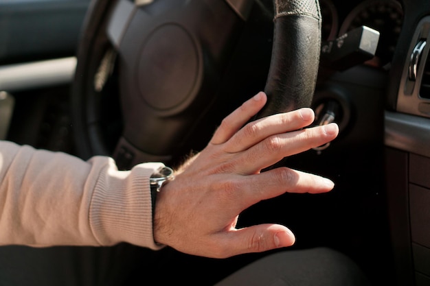 La mano de un hombre en un volante. Guarnecido del volante en mal estado en un coche. Reloj en mano