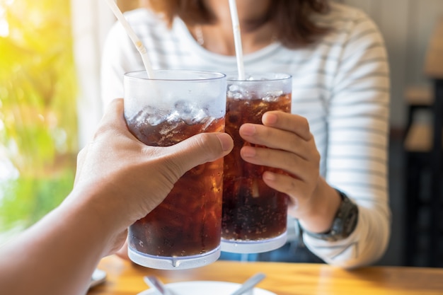 Mano de hombres y mujeres dando vaso de bebida gaseosa