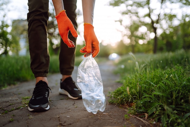 Foto la mano de los hombres recoge basura plástica para limpiar en el parque. voluntario con guantes protectores recoge botellas de plástico.