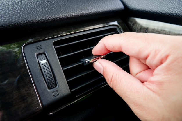 La mano humana ajusta la dirección del viento del aire acondicionado del coche en la cabina