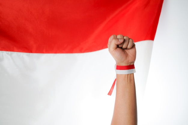Mano humana apretada en un puño con cinta roja y blanca con fondo de bandera indonesia
