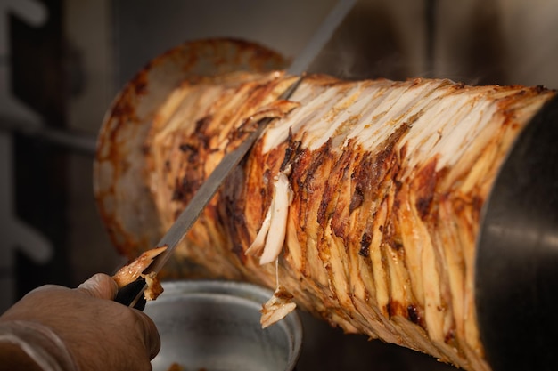 Mano humana cortando con cuchillo carne para Shawarma
