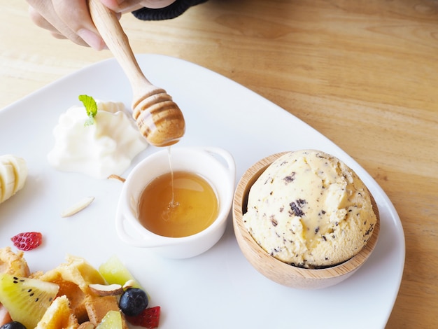 Mano humana con cucharón de miel para el postre