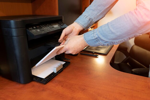 La mano humana está volviendo a cargar el papel en la bandeja de la impresora