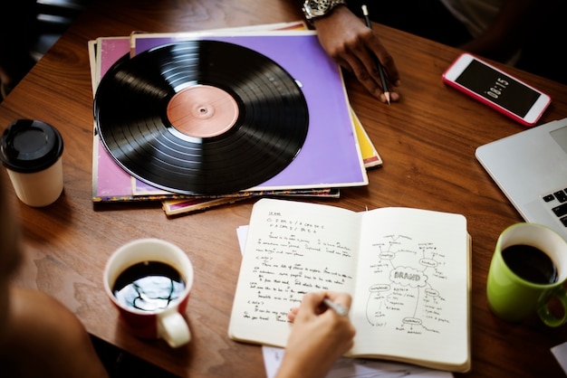 Mano humana que escribe el concepto de la música del disco de vinilo del cuaderno