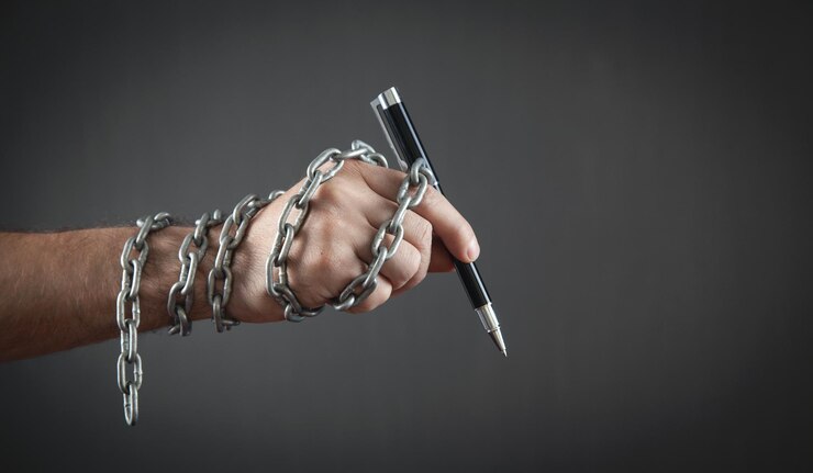 Foto mano humana sosteniendo un bolígrafo atado con cadenas.