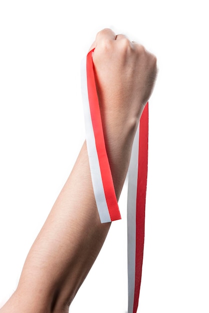 Mano humana sosteniendo una cinta con el color rojo y blanco de la bandera de Indonesia