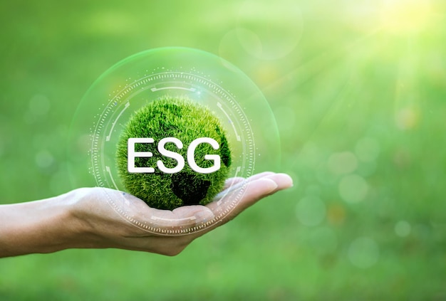 Mano humana sosteniendo un icono ESG de tierra verde con luz solar sobre un fondo verde. para Medio Ambiente Soci