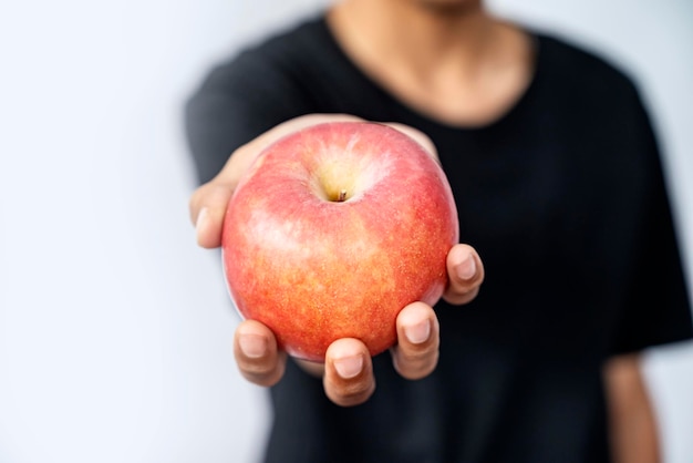 Una mano humana sosteniendo una manzana con un fondo blanco.