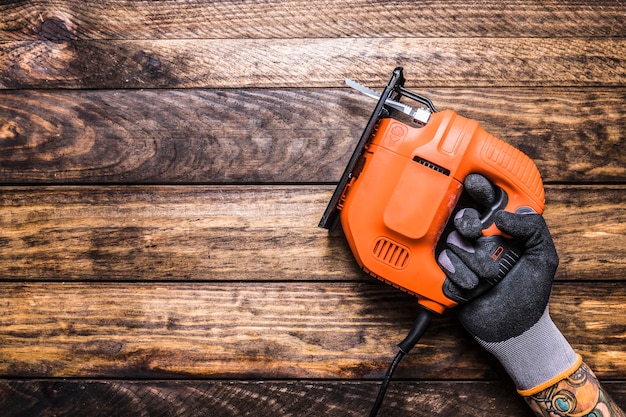 Mano humana sosteniendo rompecabezas eléctrico sobre fondo de madera