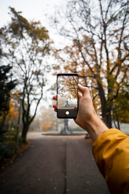 Foto la mano humana sosteniendo un teléfono inteligente en otoño en un parque