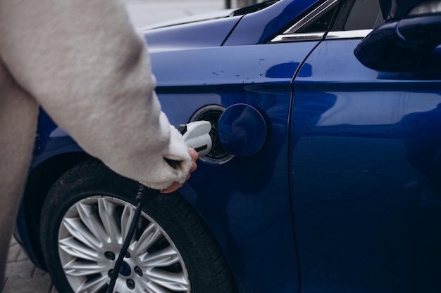 La mano humana sostiene la carga del automóvil eléctrico, conecte al automóvil