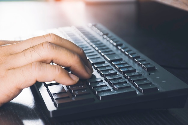 Foto mano humana con teclado de computadora en el escritorio