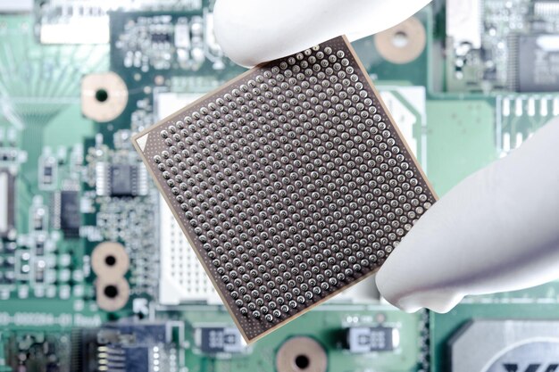 La mano del ingeniero informático con guantes de látex trae los componentes de cambio de memoria del procesador de la CPU de la computadora al procesador de socket para el mantenimiento. Concepto de tecnología y desarrollo. Primer plano. Macro. Enfoque selectivo.