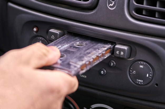 Foto mano insertando un casete de música en el reproductor de cintas de coche antiguo