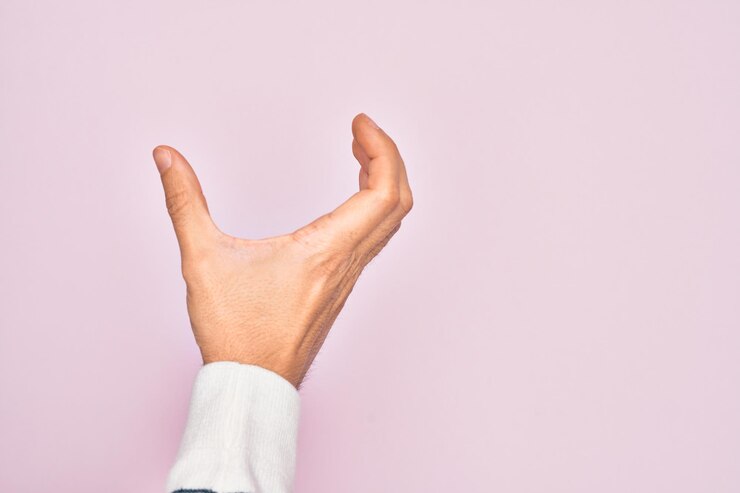Foto la mano de un joven caucásico mostrando los dedos sobre un fondo rosa aislado recogiendo y tomando una cosa invisible sosteniendo un objeto con los dedos mostrando el espacio