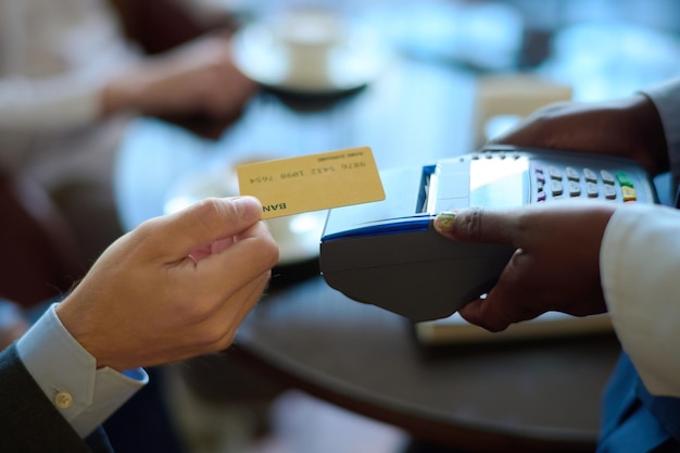 Mano de joven empresario con tarjeta de crédito sobre terminal de pago