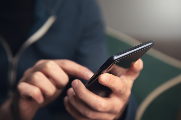 La mano del joven sosteniendo un teléfono inteligente