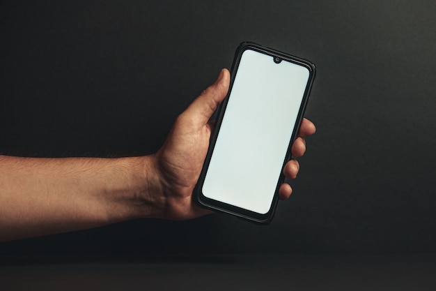 Mano joven sosteniendo un teléfono con una pantalla blanca