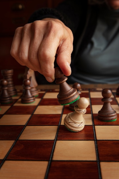 Foto mano jugando al ajedrez en el tablero clásico