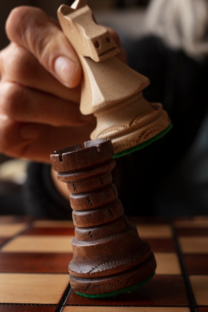 Foto mano jugando al ajedrez en el tablero clásico