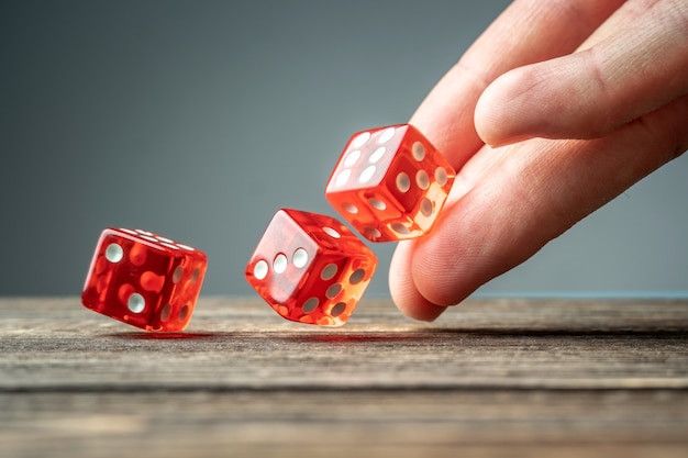 Foto la mano está lanzando dados rojos sobre la mesa de madera. el concepto de casino y la suerte de ganar