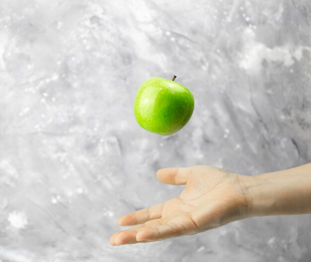 Mano lanzando una manzana verde