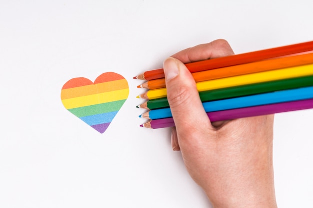 Foto mano con lápices de colores y el icono del corazón como lgbt signo