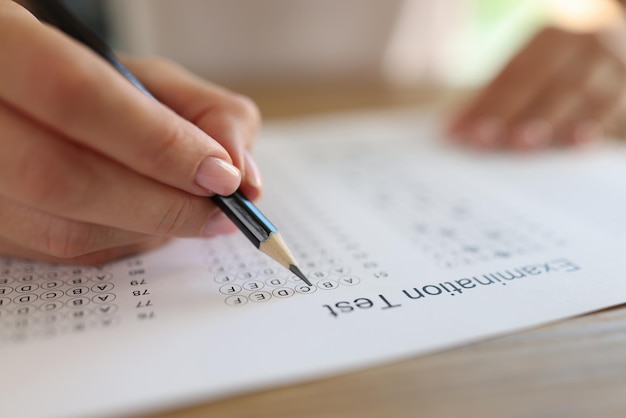 Mano con lápiz en papel de prueba de examen cerca de la escuela y la universidad de estudio de educación