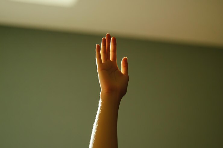 Foto la mano levantada en la luz del sol contra un fondo verde
