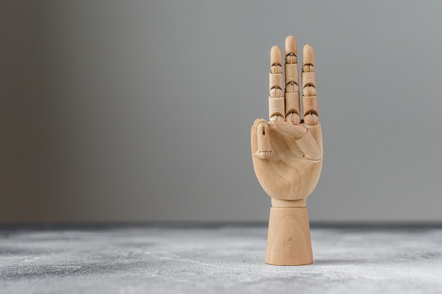 Foto la mano de madera muestra tres dedos levantados. el concepto de comunicación.