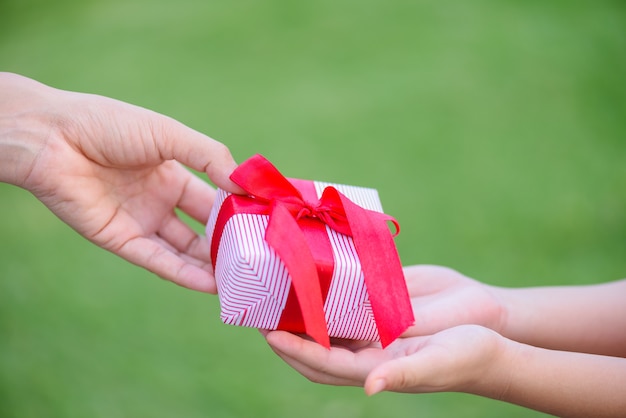 Foto mano de madre dando una caja de regalo a su hijo