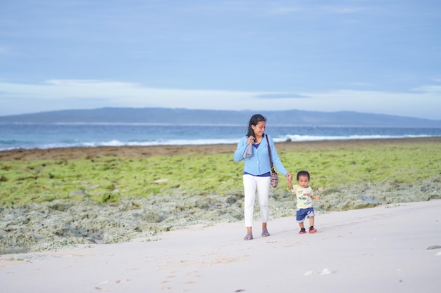 de la mano madre e hija caminando en la playa