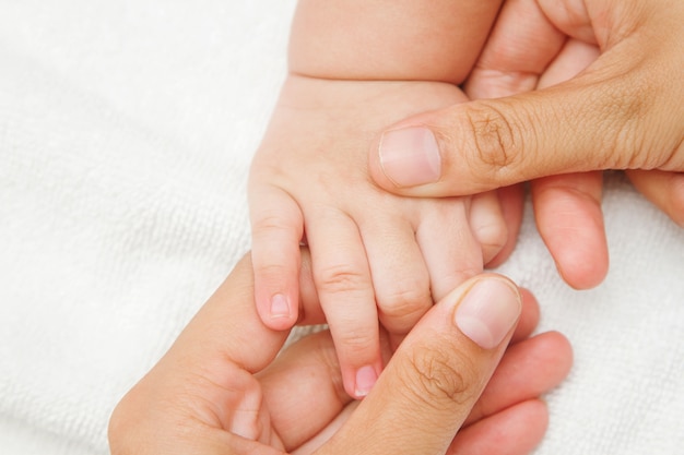 Mano de la madre masajeando la mano de su bebé