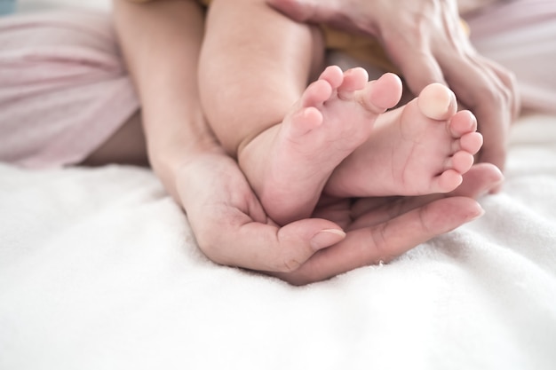 Foto mano de la madre, sostener, pie del bebé