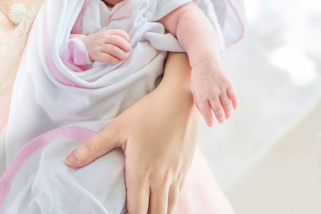 La mano de la madre sosteniendo a su bebé.