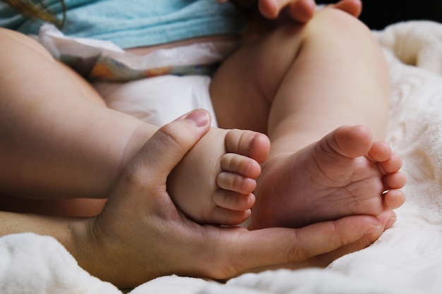 La mano de la madre sostiene las lindas piernas del bebé