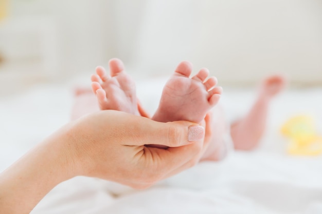 La mano de la madre sostiene las piernas del bebé, madre e hijo.