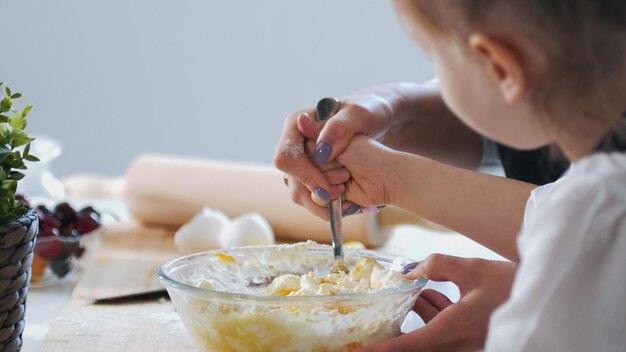 Mano de madre con su hijo mezclando la masa para preparar panqueques