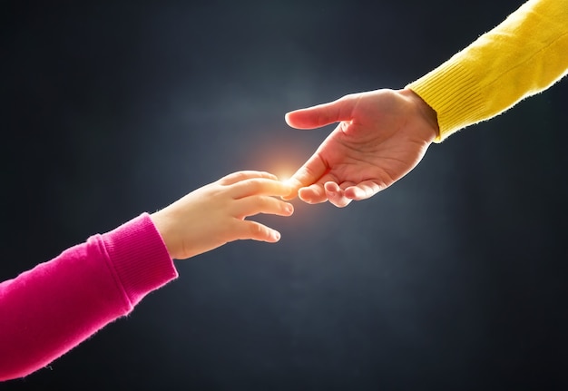 La mano de la madre toca la mano del niño pequeño sobre fondo gris