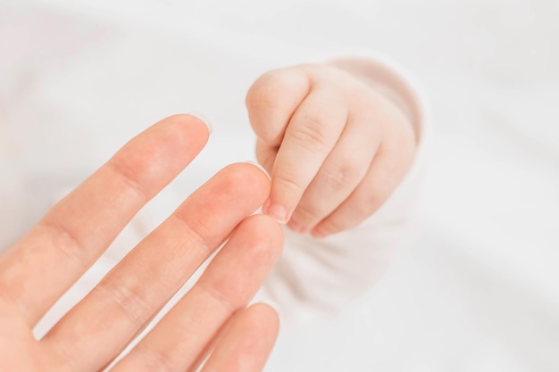 La mano de las madres ucranianas sostiene los dedos del bebé recién nacido Cerrar el vínculo emocional del Día de la madre entre madre e hijo