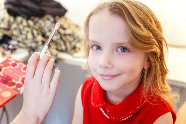 Mano del maestro de maquillaje aplicando sombra de ojos para modelo de niña bonita